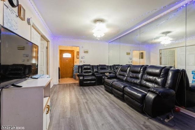 home theater room featuring light wood-type flooring, ceiling fan, and ornamental molding