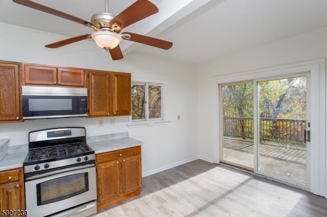 kitchen featuring beam ceiling, ceiling fan, light wood-type flooring, and appliances with stainless steel finishes