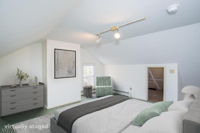 carpeted bedroom with baseboard heating, a walk in closet, rail lighting, and vaulted ceiling