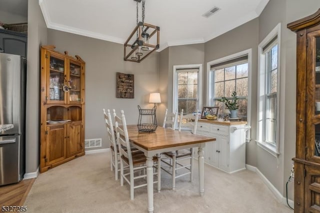 carpeted dining room with ornamental molding