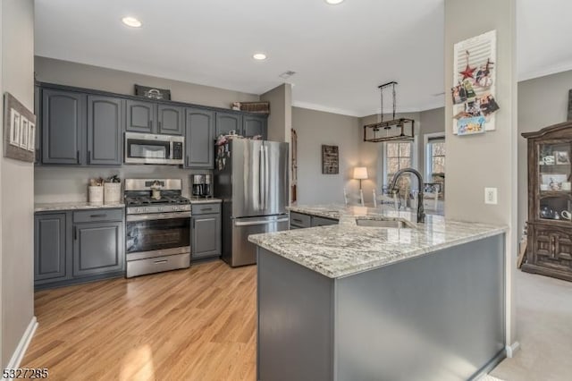 kitchen featuring gray cabinetry, sink, hanging light fixtures, stainless steel appliances, and light wood-type flooring