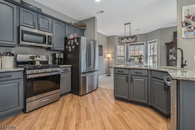 kitchen with decorative light fixtures, gray cabinets, light wood-type flooring, and appliances with stainless steel finishes