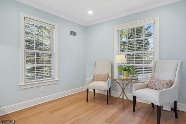 sitting room featuring hardwood / wood-style floors, a healthy amount of sunlight, and ornamental molding