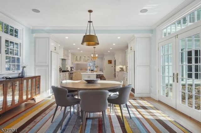 dining space with french doors, light hardwood / wood-style flooring, and ornamental molding