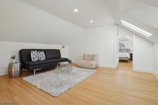 living room featuring light hardwood / wood-style flooring and vaulted ceiling with skylight