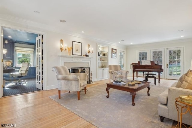 living room with french doors, light hardwood / wood-style floors, built in features, and ornamental molding