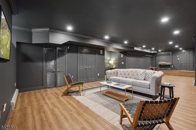 cinema room with crown molding, light hardwood / wood-style flooring, and a baseboard radiator