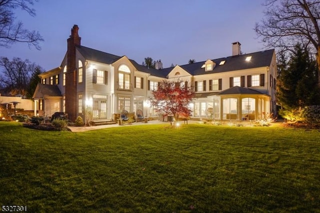 back house at dusk featuring a yard