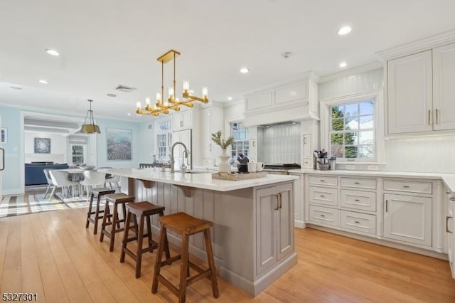 kitchen with a center island with sink, white cabinets, and hanging light fixtures