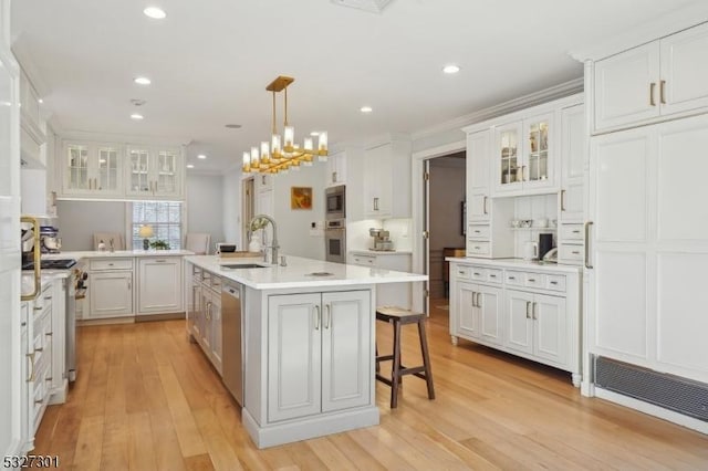 kitchen featuring sink, pendant lighting, a kitchen island with sink, a breakfast bar, and white cabinets