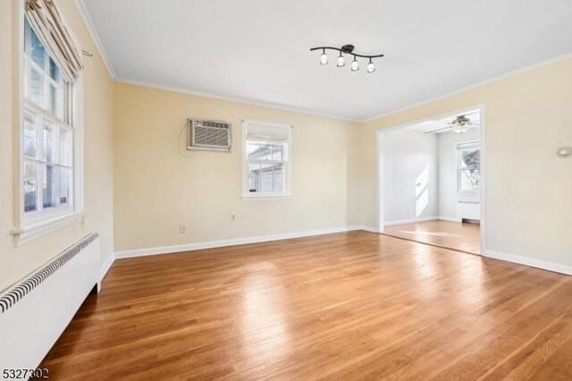 empty room with radiator, ceiling fan, crown molding, hardwood / wood-style flooring, and an AC wall unit