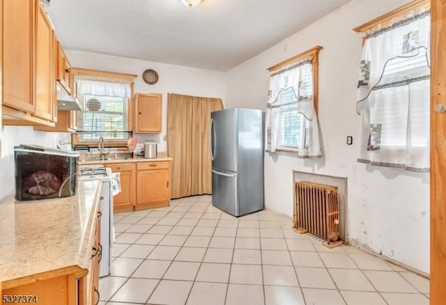 kitchen with light brown cabinets, sink, stainless steel fridge, white range oven, and radiator heating unit