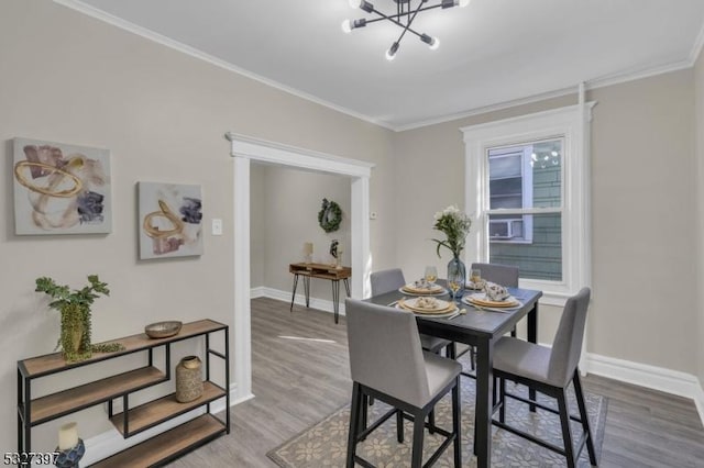 dining space with hardwood / wood-style flooring, ornamental molding, and an inviting chandelier