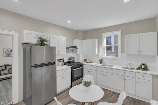 kitchen with white cabinets, sink, stainless steel appliances, and hardwood / wood-style flooring