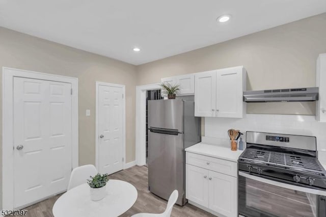 kitchen featuring appliances with stainless steel finishes, ventilation hood, white cabinetry, and light hardwood / wood-style flooring