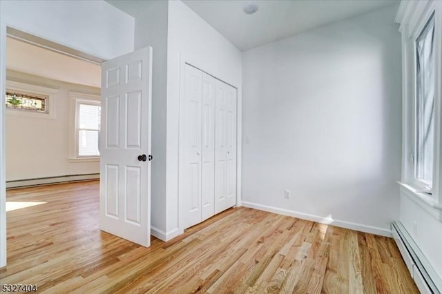 unfurnished bedroom featuring a baseboard radiator, a closet, and light hardwood / wood-style floors