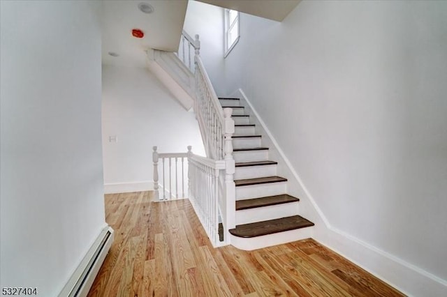 stairway featuring baseboard heating and hardwood / wood-style floors