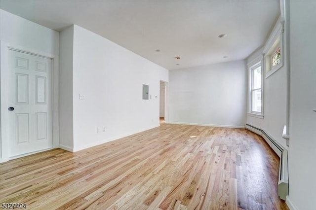 empty room featuring electric panel and light hardwood / wood-style flooring