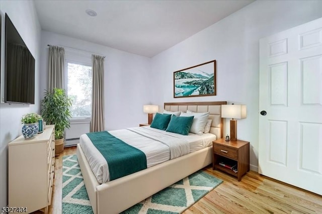bedroom featuring light wood-type flooring and a baseboard radiator
