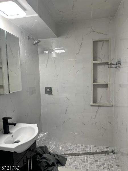 bathroom featuring vanity, tile walls, and tiled shower