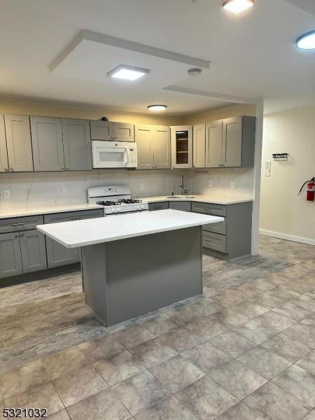 kitchen featuring white appliances, a center island, and gray cabinetry