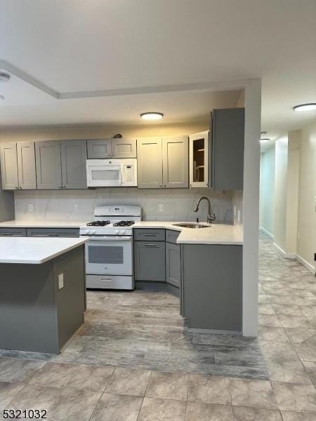 kitchen featuring white appliances, gray cabinetry, and sink