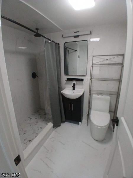 bathroom featuring toilet, vanity, and walk in shower