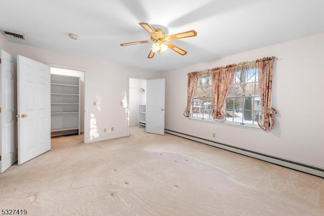 unfurnished bedroom with light carpet, a baseboard heating unit, ceiling fan, a spacious closet, and a closet