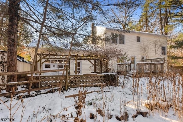 snow covered back of property with a deck