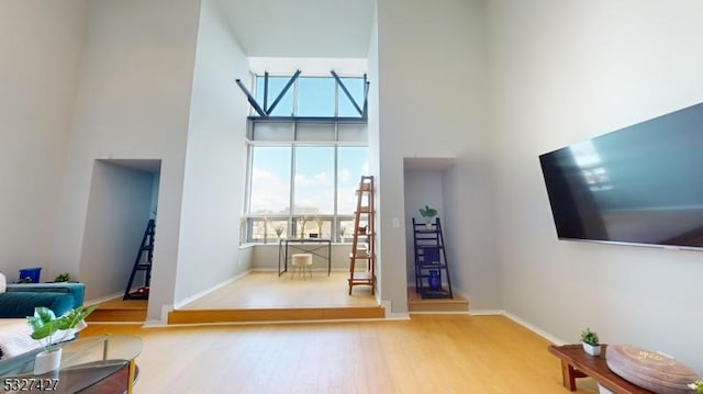 living room featuring a towering ceiling and light wood-type flooring