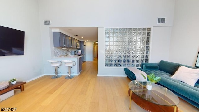 living room with light hardwood / wood-style flooring and a towering ceiling