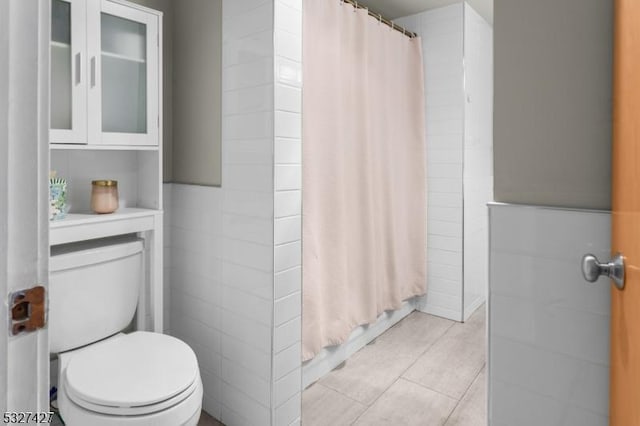 bathroom featuring tile patterned flooring, toilet, and tile walls