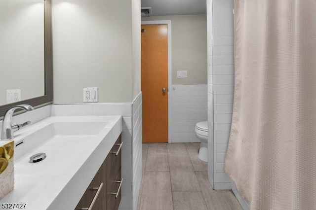 bathroom with hardwood / wood-style flooring, vanity, tile walls, and toilet