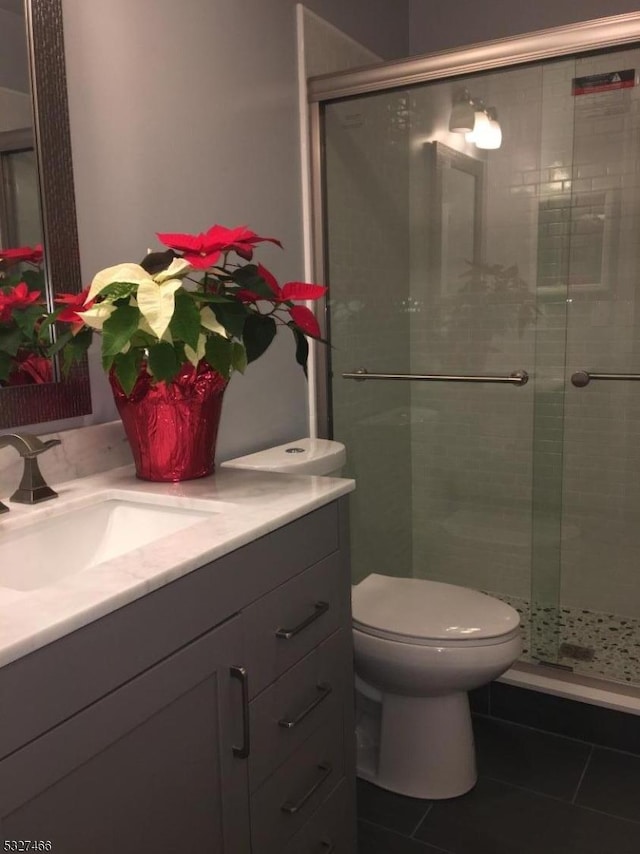 bathroom with toilet, an enclosed shower, tile patterned flooring, and vanity