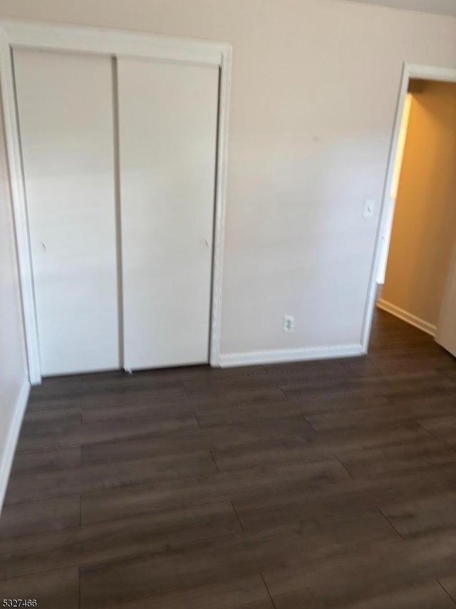 unfurnished bedroom with dark hardwood / wood-style flooring and a closet