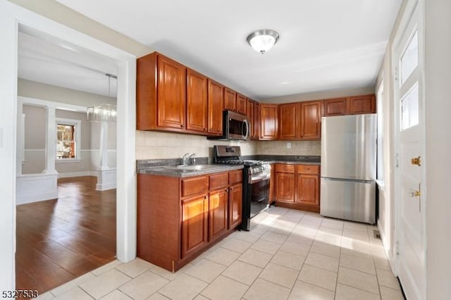 kitchen with backsplash, sink, light hardwood / wood-style flooring, ornate columns, and stainless steel appliances