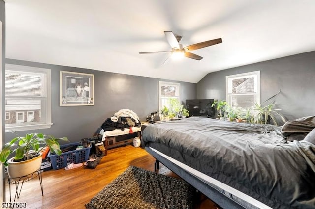 bedroom with ceiling fan, hardwood / wood-style floors, and vaulted ceiling