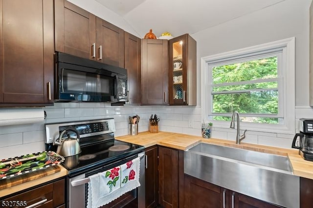 kitchen featuring butcher block counters, sink, backsplash, lofted ceiling, and stainless steel range with electric stovetop