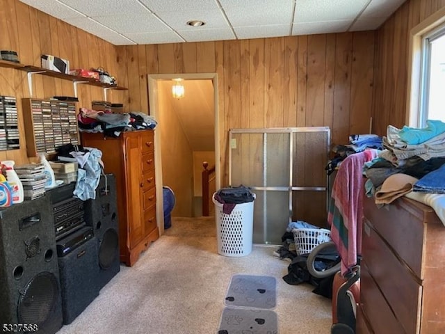 misc room featuring carpet flooring, a drop ceiling, and wooden walls