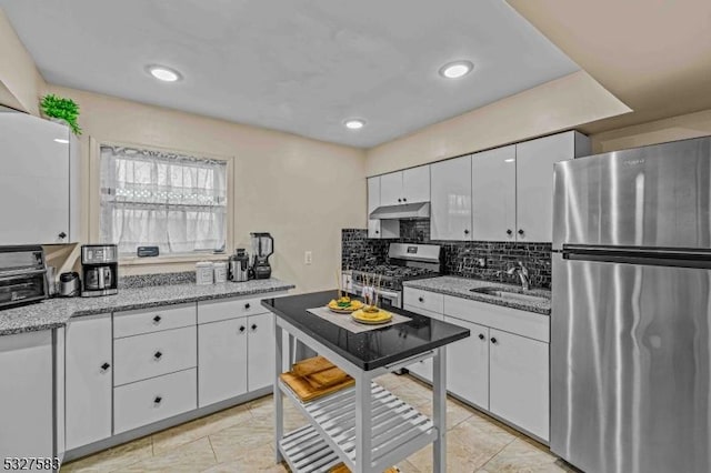 kitchen with backsplash, light stone counters, stainless steel appliances, sink, and white cabinetry