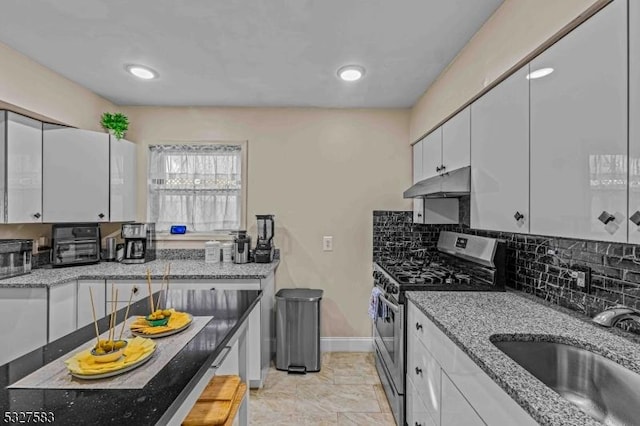 kitchen featuring stainless steel gas range oven, sink, light stone countertops, tasteful backsplash, and white cabinetry