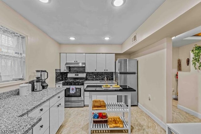 kitchen featuring decorative backsplash, appliances with stainless steel finishes, white cabinetry, and light stone countertops