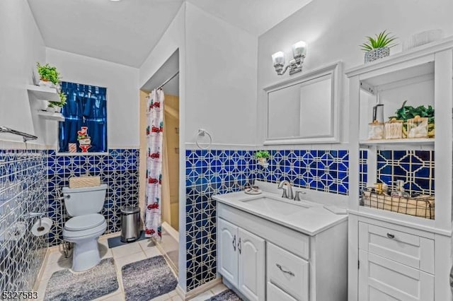 full bathroom with tile patterned flooring, shower / bath combination with curtain, toilet, vanity, and tile walls