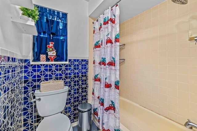 bathroom featuring shower / bath combination with curtain, toilet, and tile walls