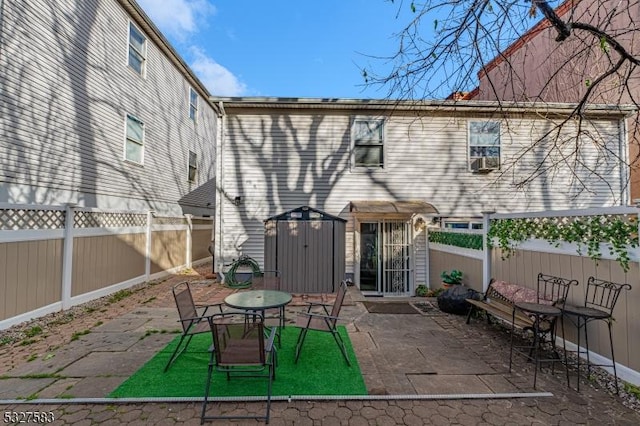 rear view of property featuring a storage unit and a patio area