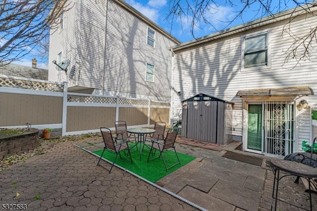 rear view of property with a storage unit and a patio area