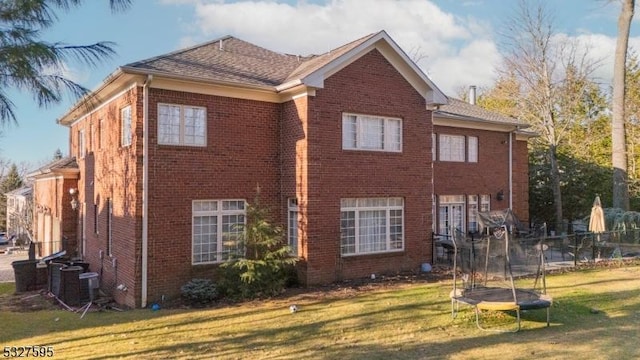 view of side of home with central AC, a yard, and a trampoline