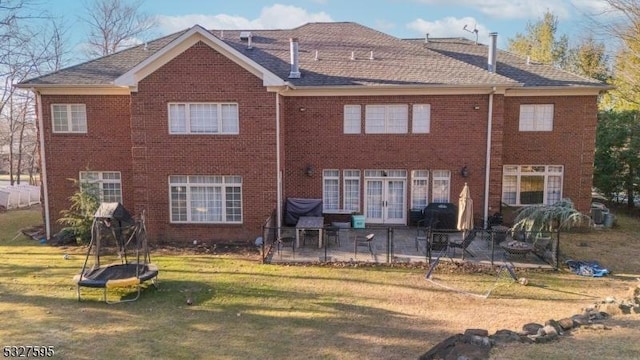 rear view of property with french doors, a patio area, and a lawn