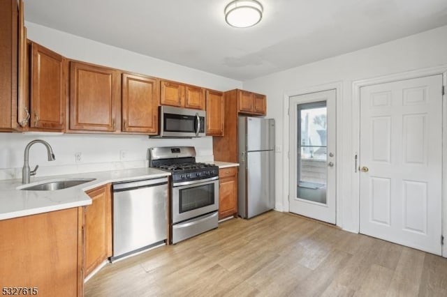 kitchen with sink, stainless steel appliances, and light hardwood / wood-style floors