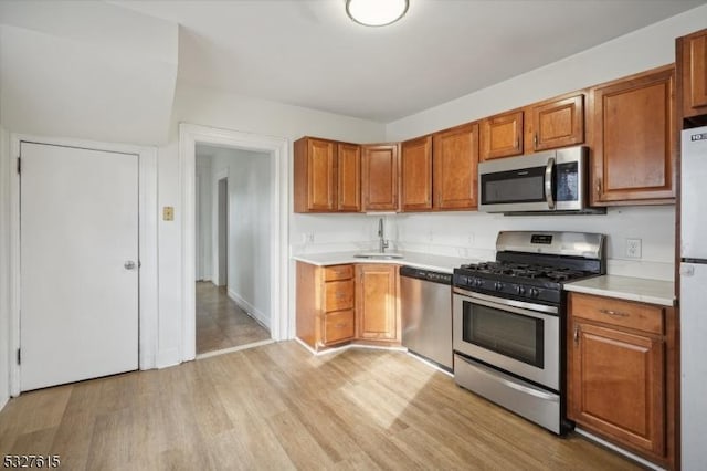 kitchen with light wood-type flooring, sink, and appliances with stainless steel finishes